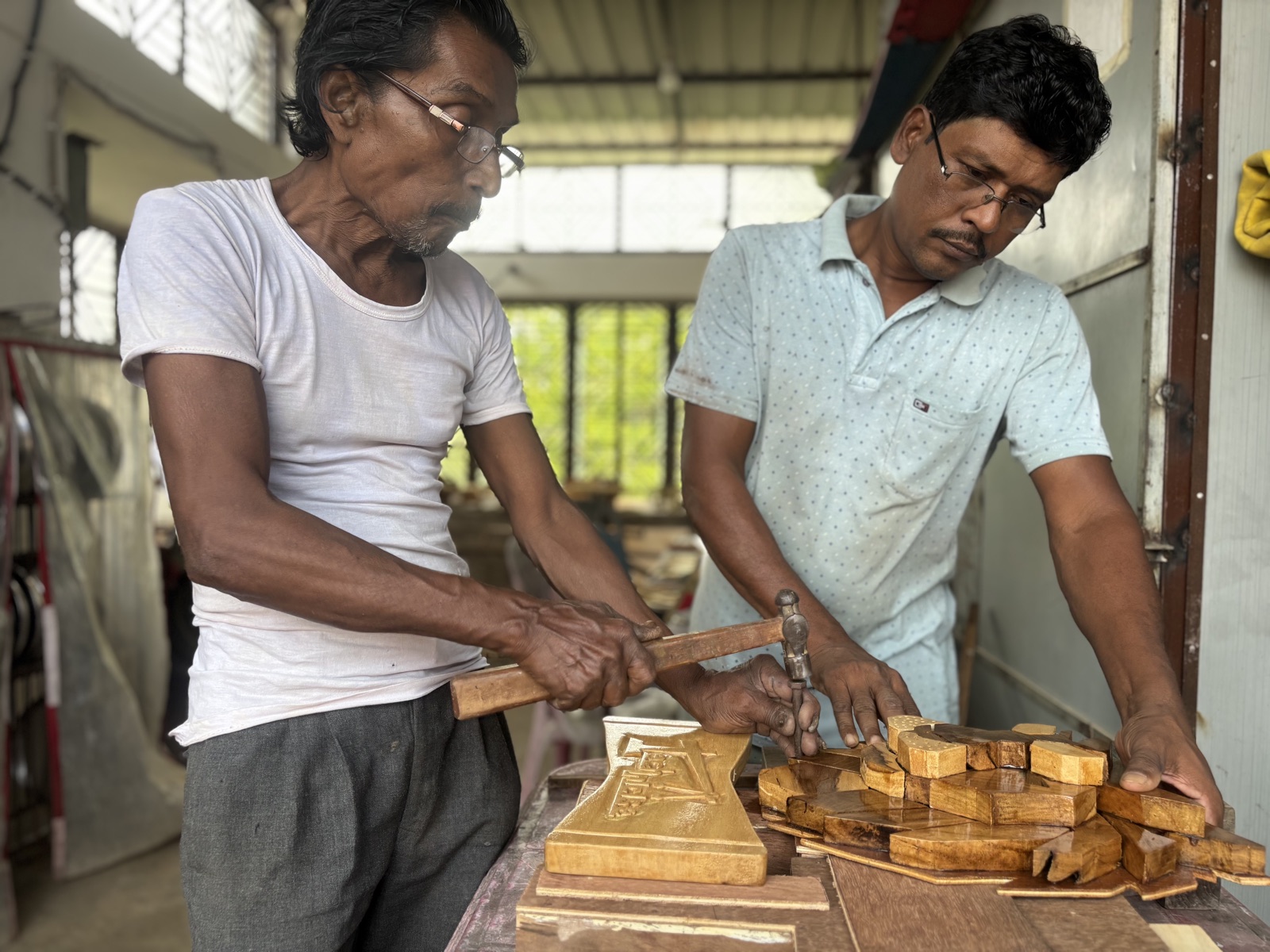 Two artisans fixing the carved Technicise base to the award